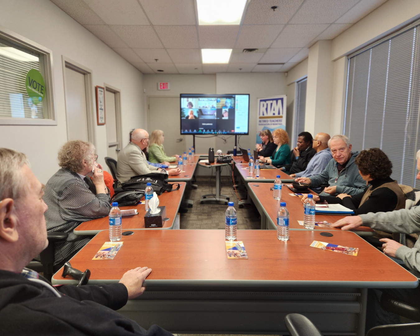 people-watching-virtual-meeting-from-around-boardroom-table