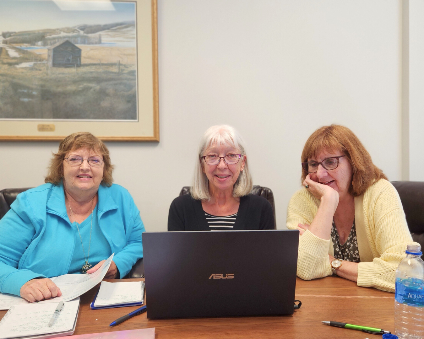 three-people-sit-behind-a-laptop-screen